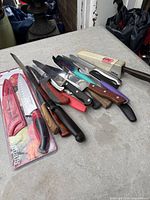 Pile of assorted knives and sharpener on table