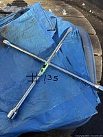 Full view of chrome 4-way lug wrench on blue tarp