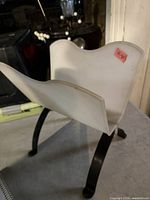 Overall view of white plastic magazine holder on black metal legs