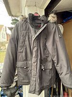 Front view of dark grey Canadiana hooded winter jacket on hanger
