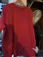 Front view of red Under Armour HeatGear T-shirt hanging on hanger