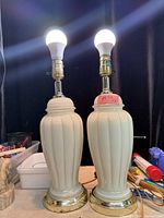 Front view of both matching white ceramic lamps with bulbs lit