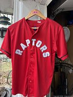 Front view of red Raptors jersey showing buttons and chest lettering