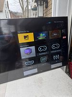 Front view of Sharp Roku TV powered on showing apps menu