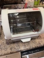 Front view of Baby George rotisserie oven showing transparent door and interior spit