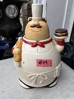 Front view of ceramic chef cookie jar with rolling pin and dessert