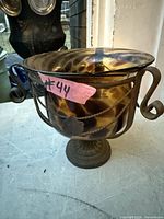 Front view of spotted glass vase in iron stand