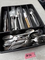 Top view of mixed cutlery organized in black tray