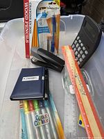 Overview showing packaged pencils, mechanical pencils, stapler, calculator, rulers, memo pad, marker pack and loose writing instruments
