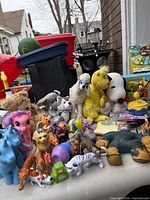Overview of entire toy lot on table showing plush toys, My Little Pony, unicorns and assorted animal figurines