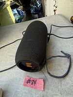 Black cylindrical Monster Bluetooth speaker with braided strap and charging cable