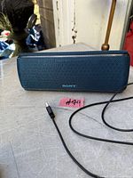 Front view of blue Sony portable Bluetooth speaker with USB-C charging cable