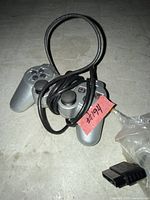 Front view of silver Sony DualShock 2 controller with cable coiled