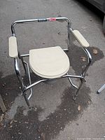 Commode front view with lid closed showing chrome frame and padded arms