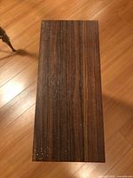 Top view of rectangular wood veneer side table top with visible paint splatter and wear