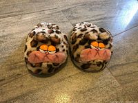 Top view of both slippers showing leopard print faux fur and Garfield-style faces