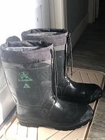 Side view of both black Kamik boots showing logo, rubber exterior and drawstring cuff