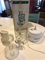 All components laid out: motor base, bowl, lid, food pusher, blade, box