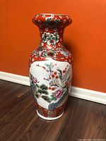 Front view of large Chinese porcelain floor vase showing bird and blossom panel and red floral ground