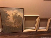 Painting and two wood frames leaning against wall
