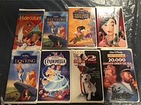 Eight Disney clamshell VHS tapes visible on plastic surface