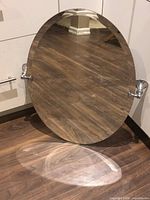Front view of oval frameless mirror with chrome swivel brackets