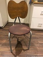 Front view of chair showing metal frame, upholstered seat, wood backrest