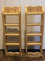 Front view of both painted wood spice racks showing four shelves and top pegs