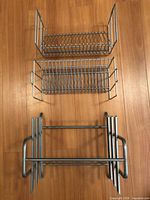 Top-down view of three stainless steel racks: utensil holder, wire basket, dish rack