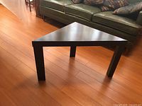 Triangular coffee table front view showing black finish and three legs