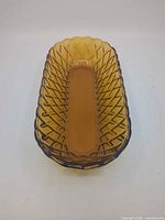 Top view of amber pressed glass dish showing diamond basketweave pattern and scalloped rim