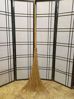 Full view of bamboo-handled twig besom broom against backdrop