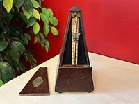 Metronome with front panel removed showing brass tempo scale and interior mechanism