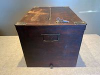 Front view of dark wooden file box showing label holder, knob, and brass hardware