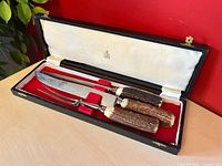 Knife and fork with stag handles resting in red velvet fitted case