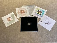 Full set laid out: coin in velvet tray, four stamp cards, tin lid, booklet