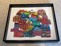 Full view of framed mixed-media artwork with colourful shrink-plastic houses