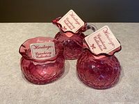 Three cranberry glass pieces with tags visible