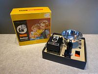 Box alongside camera and flash setup in insert