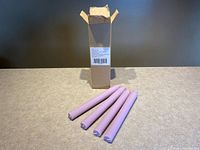 Box standing upright with four lavender fluted taper candles laid out