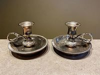Full view of both matching silver-plate chamberstick holders