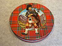 Closed tin showing tartan design and bagpiper illustration