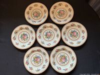 Seven of the eight floral plates arranged face up showing pattern