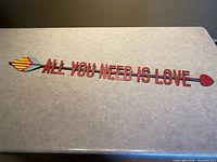 Full view of metal arrow wall sign with phrase visible