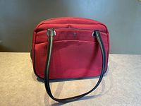 Front view of Victorinox red ballistic nylon tote showing logo badge, straps, and front pocket