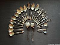 Full set of 24 flatware pieces arranged on dark background