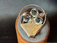 Front view of sterling silver rose basket brooch showing three roses and etched basket