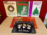 Group shot of six Christmas music books showing covers and relative sizes