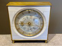Front view of brass and white rectangular Junghans zodiac table clock