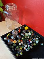 Jar and tray showing variety of marbles